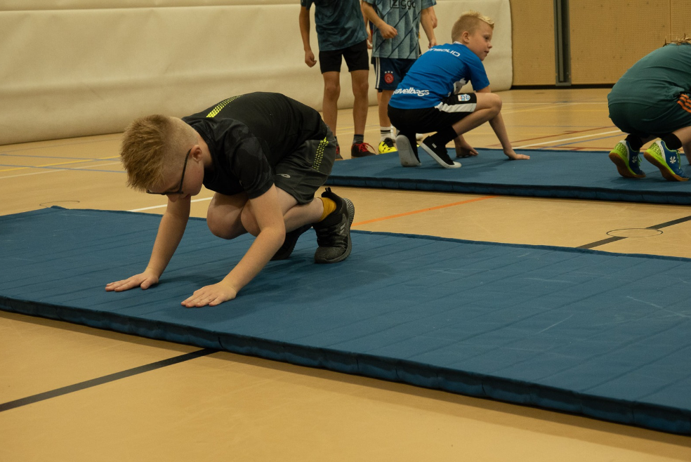 Kind leert freerunning bewegingen op een mat