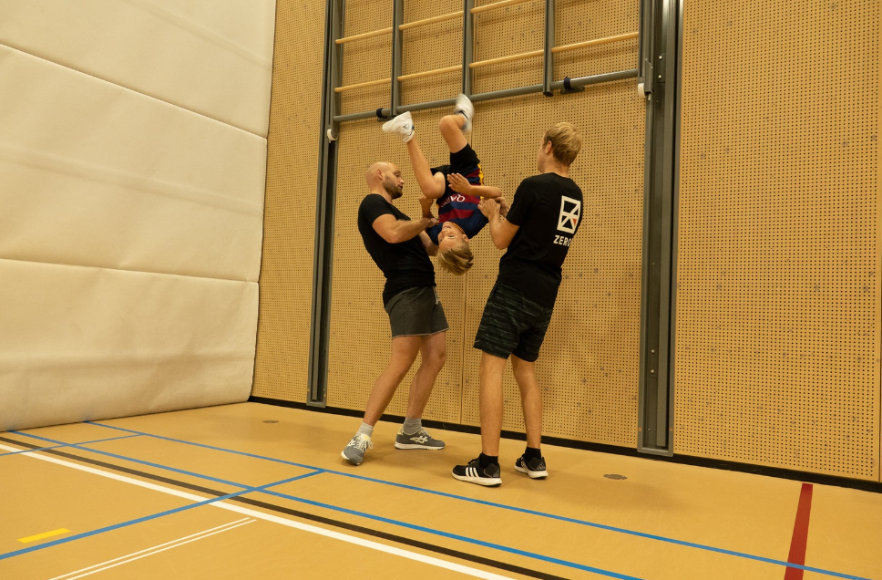 Instructeurs helpen een kind met een freerunning oefening